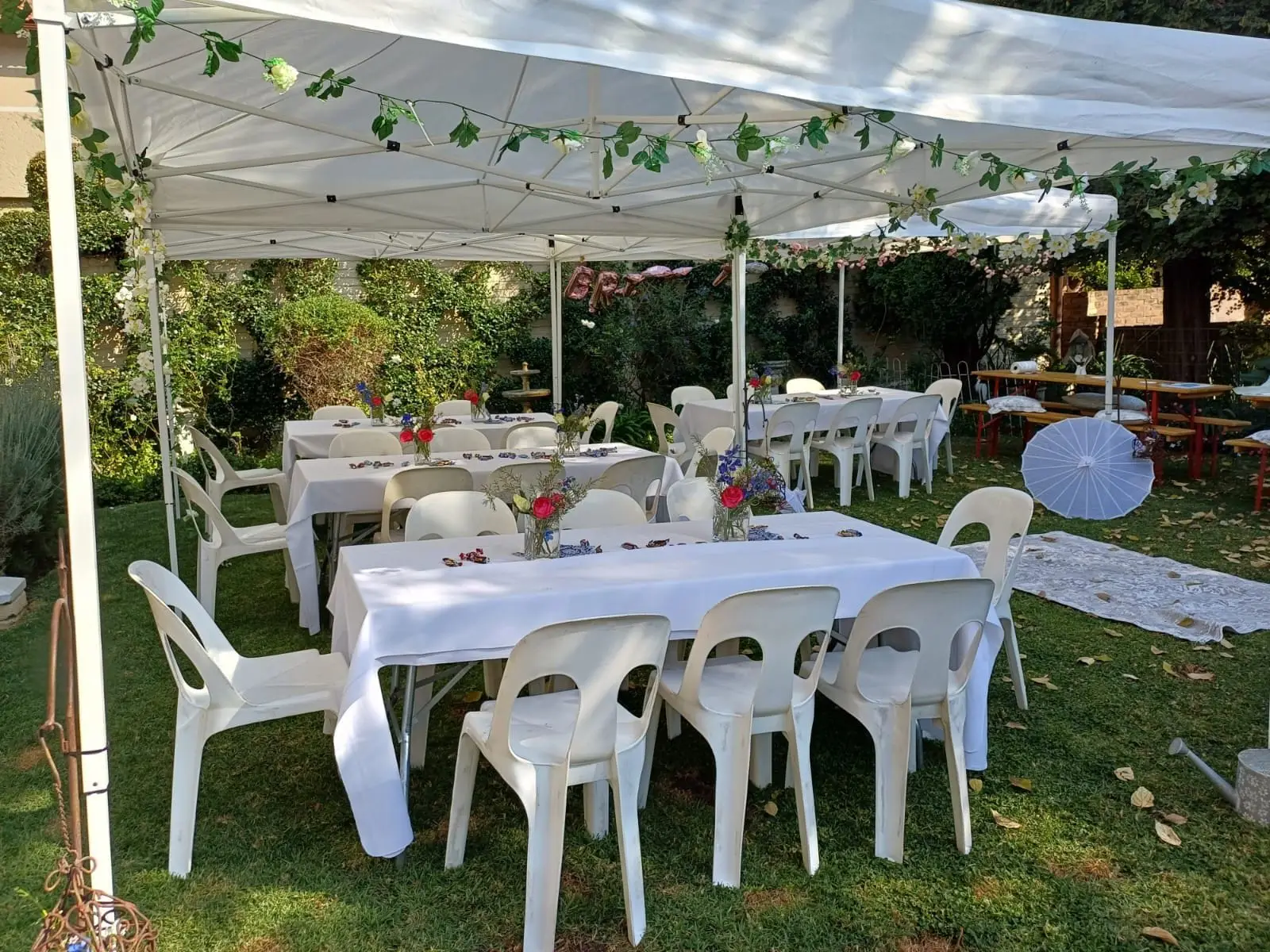Outdoor garden event setup with tables and chairs under a tent