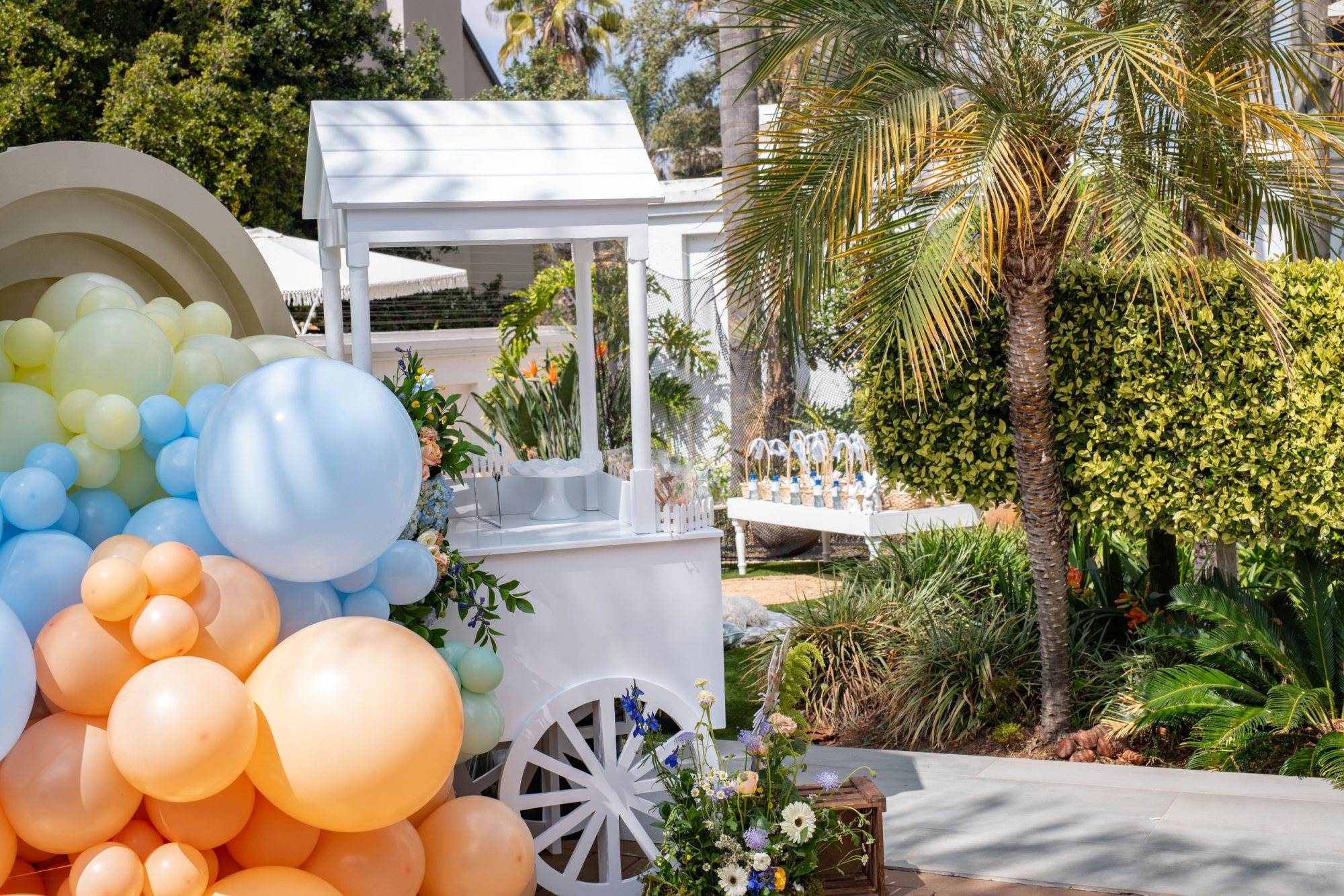 Colorful candy cart surrounded by balloons and greenery