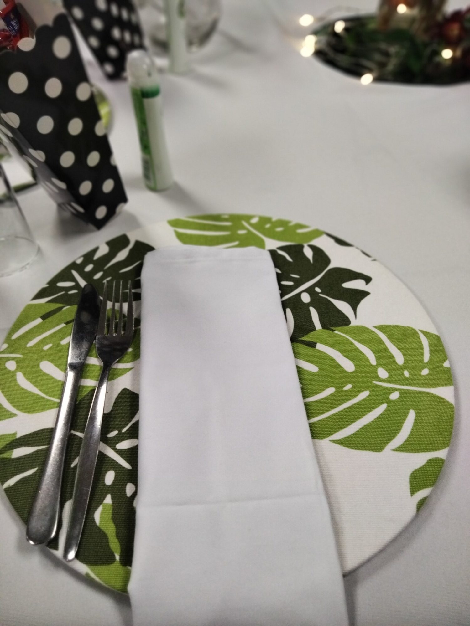 Tropical-themed table setting with leaf placemat and cutlery.