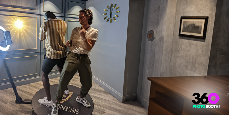 Two guests using a 360 photo booth in a stylish indoor space.