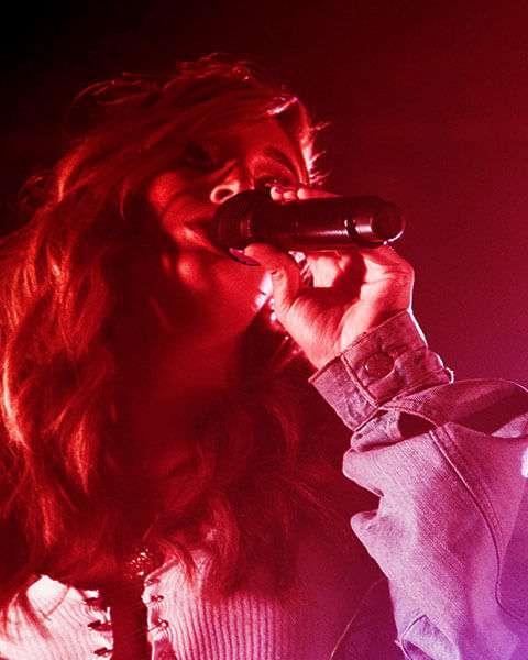 Performer singing with microphone under colored lighting