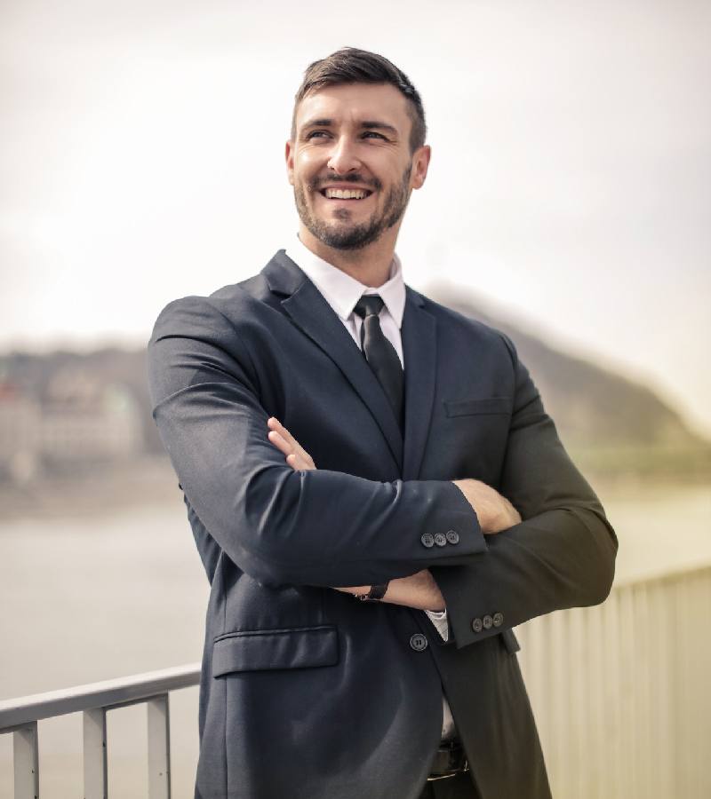 Smiling man in a suit standing with arms crossed