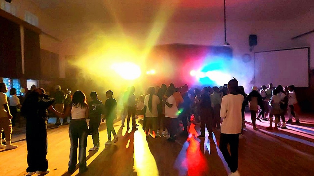 Crowd enjoying a vibrant party atmosphere with colorful lights