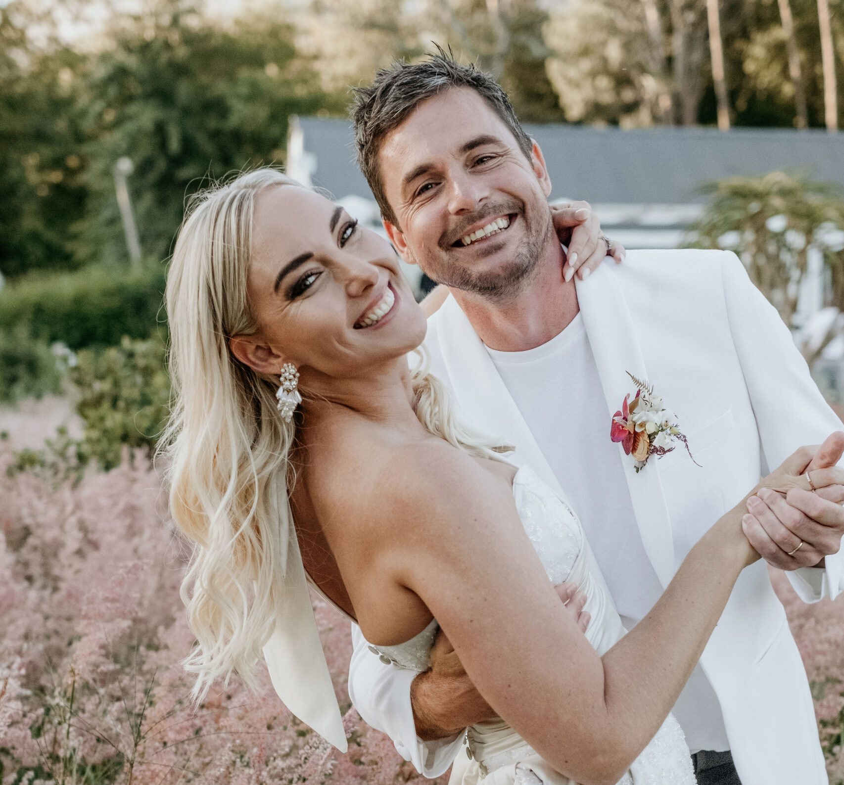 Bride and groom smiling in a floral garden
