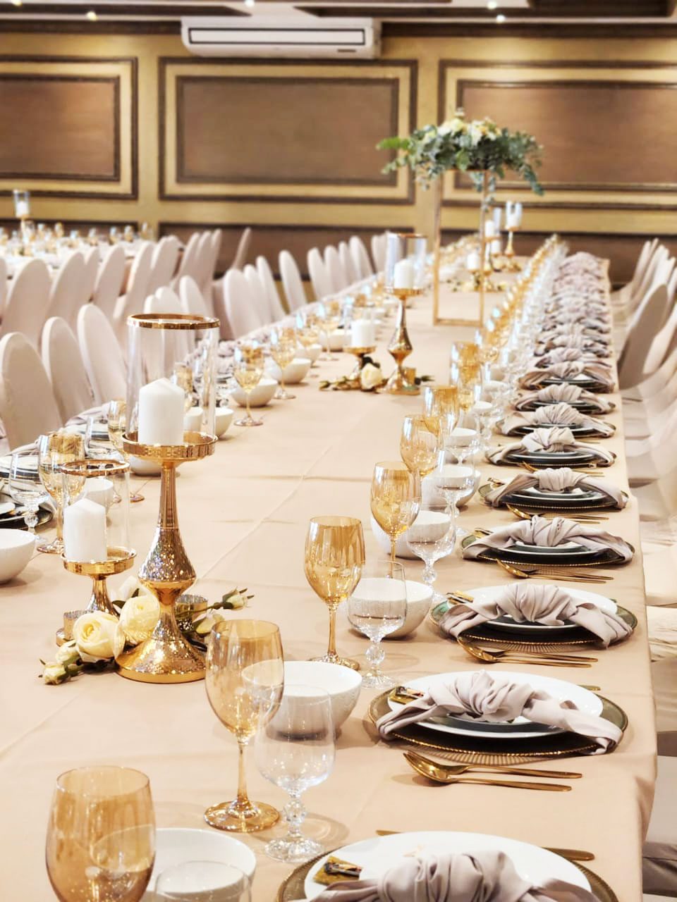 Long dining table with gold tableware and floral decor