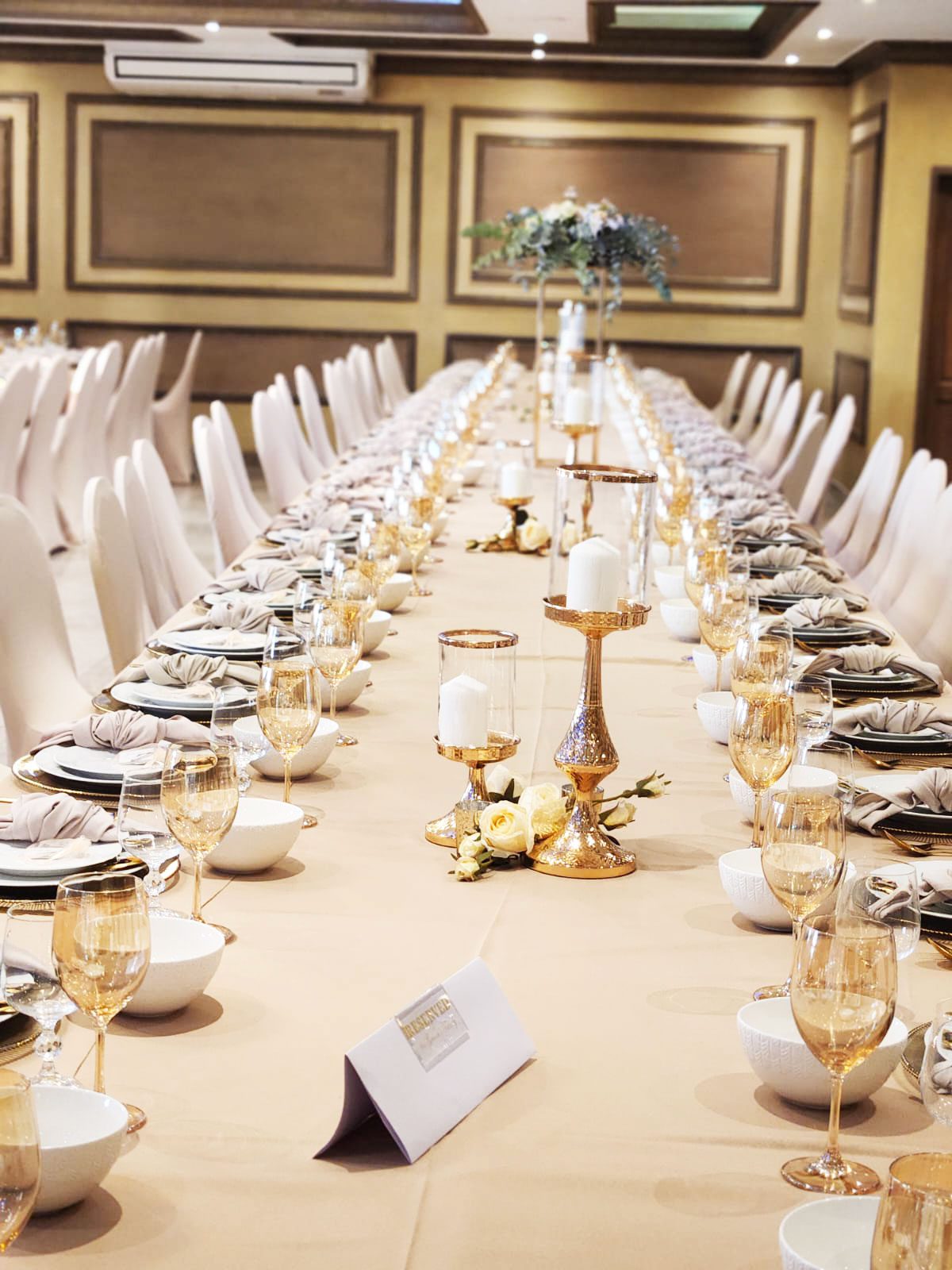 Long elegantly set table with gold accents and decor.