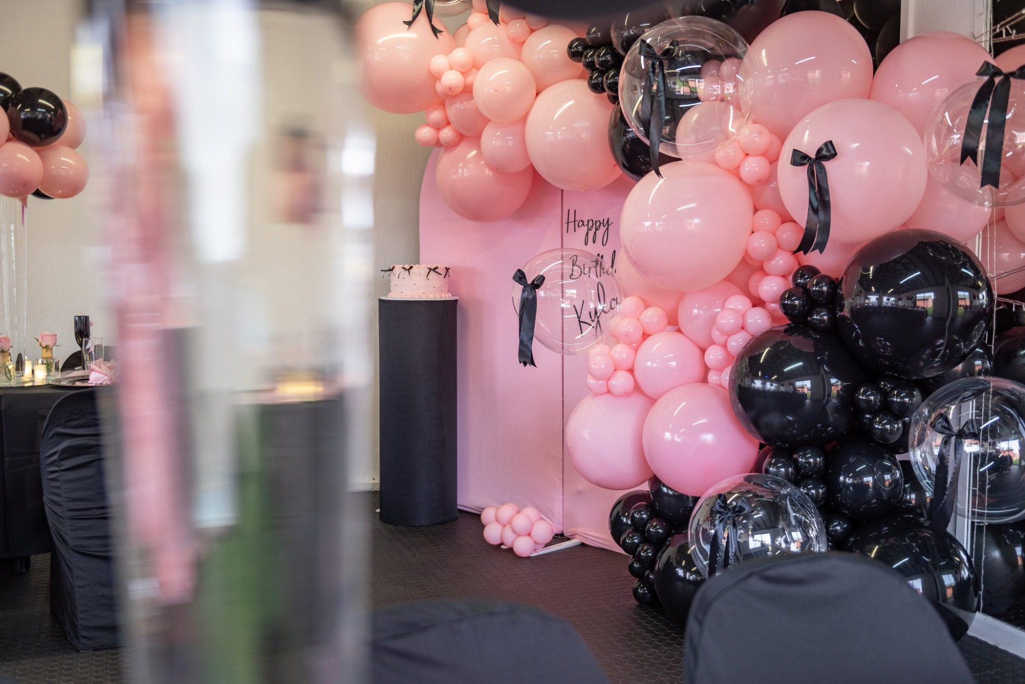 Pink and black balloon arch for a birthday party.