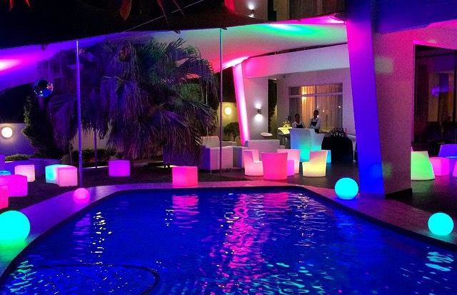 Illuminated pool area with colorful lighting and seating