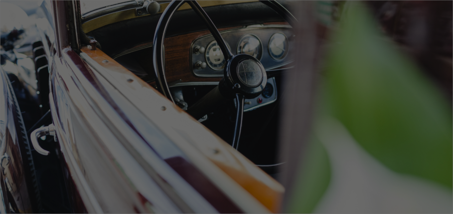 Interior view of a vintage car showing steering wheel and dashboard.
