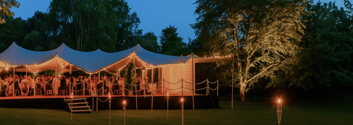 Outdoor stretch tent lit with fairy lights at dusk