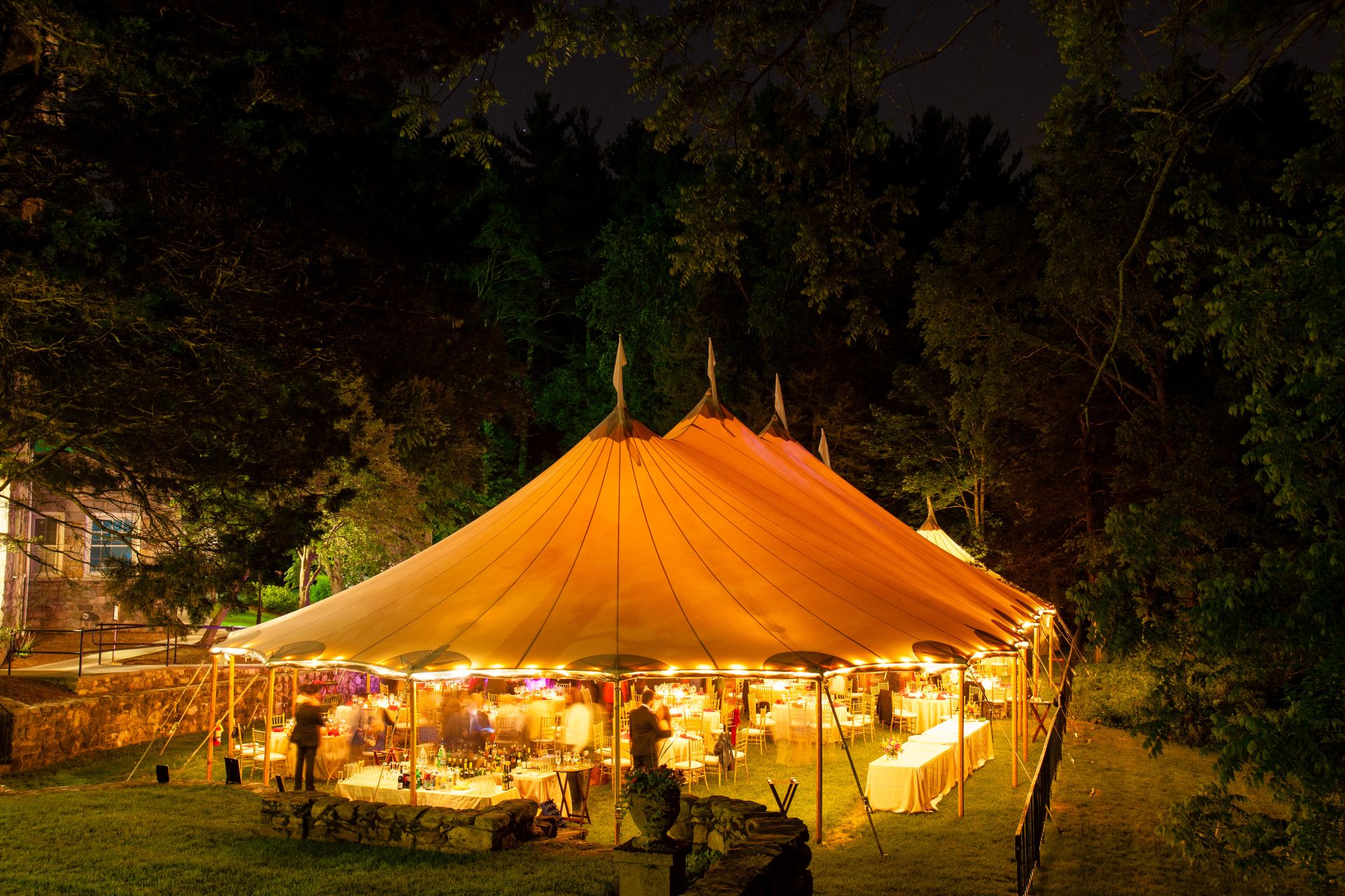 Large illuminated stretch tent set up outdoors at night.