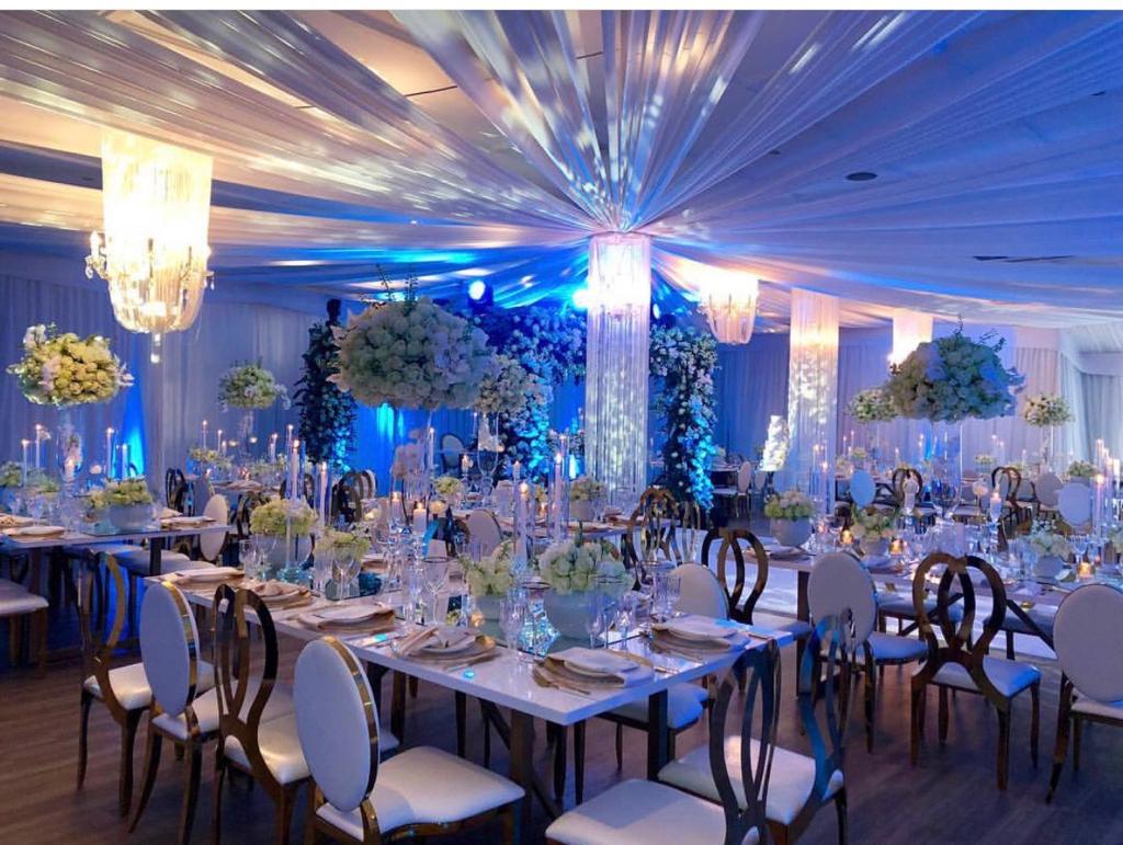 A decorated event space with white tables, chairs, and floral centerpieces.