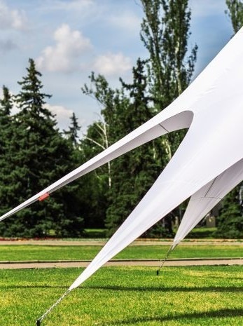 White stretch tent on grass with trees in background