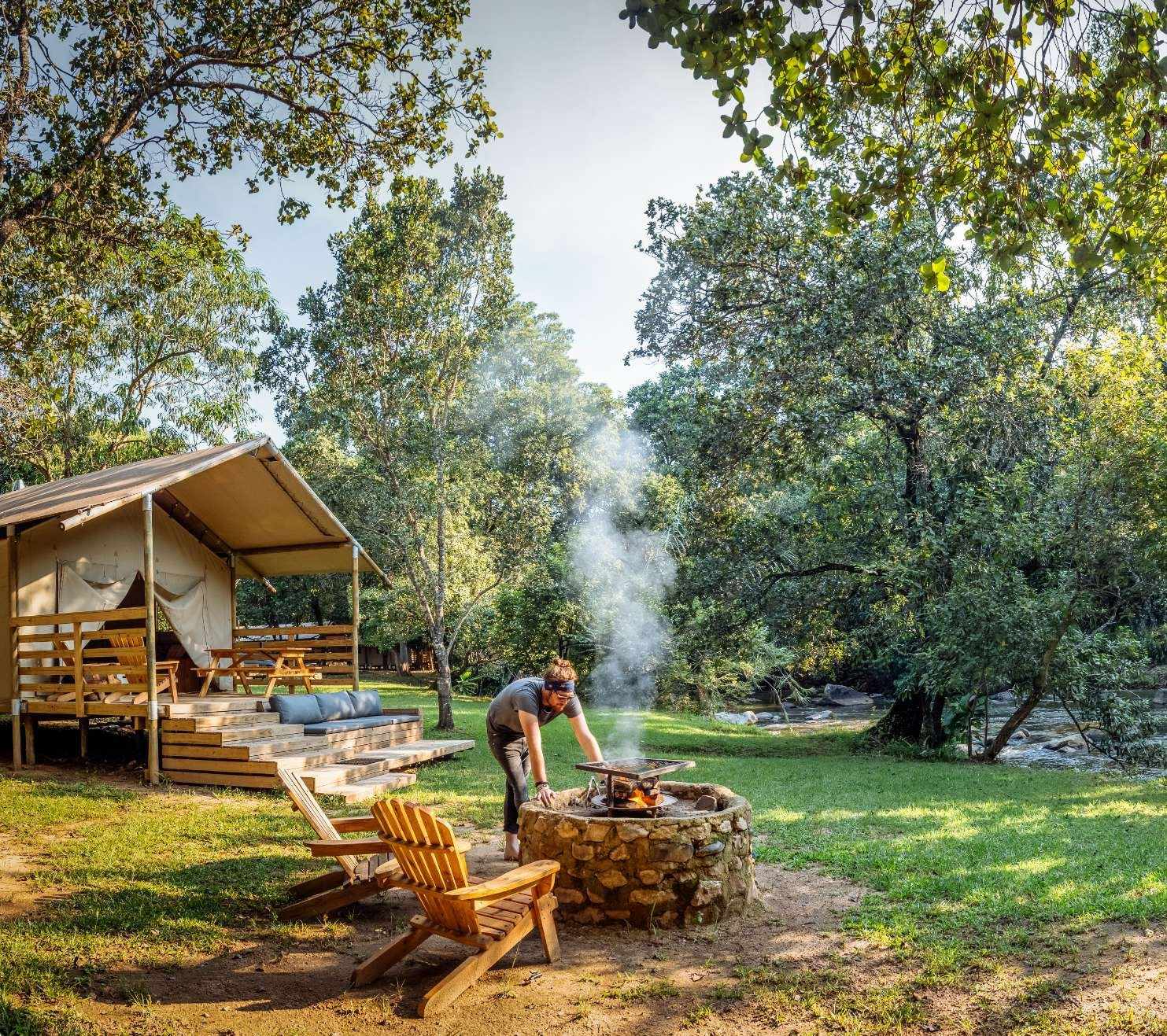 Campfire setup with a tent nearby in a natural setting.