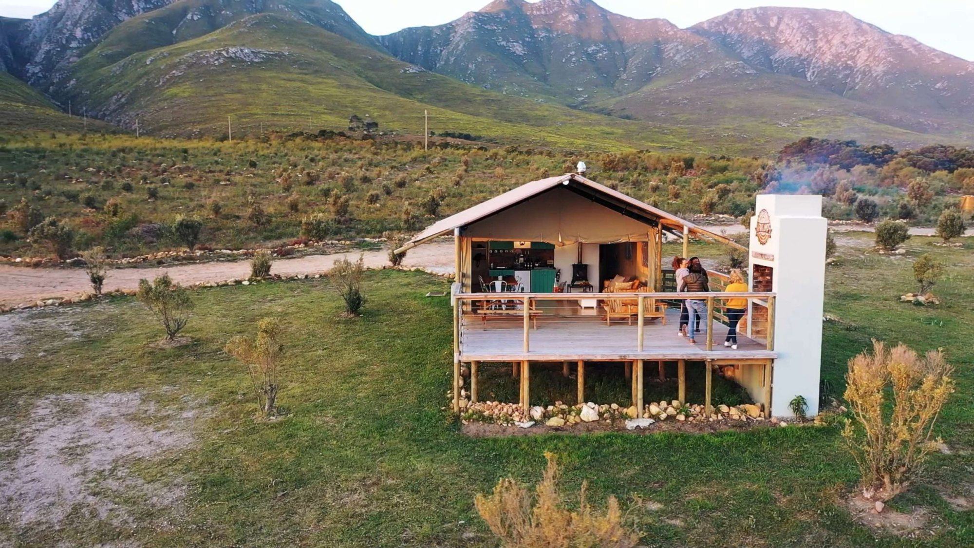 Glamping tent with a wooden deck in a mountainous landscape