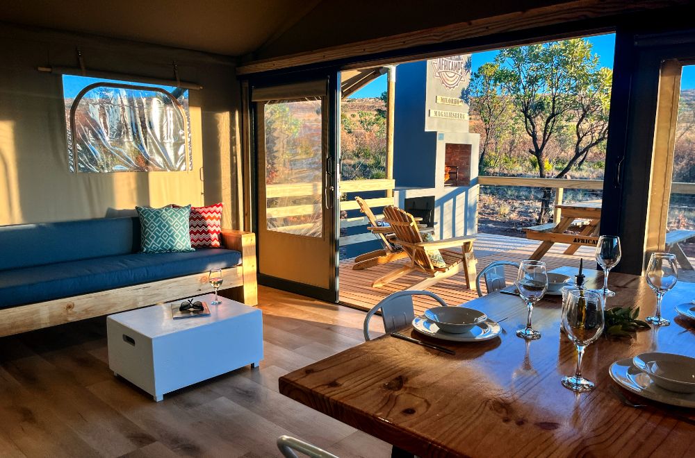Interior view of a glamping tent with seating and dining area.