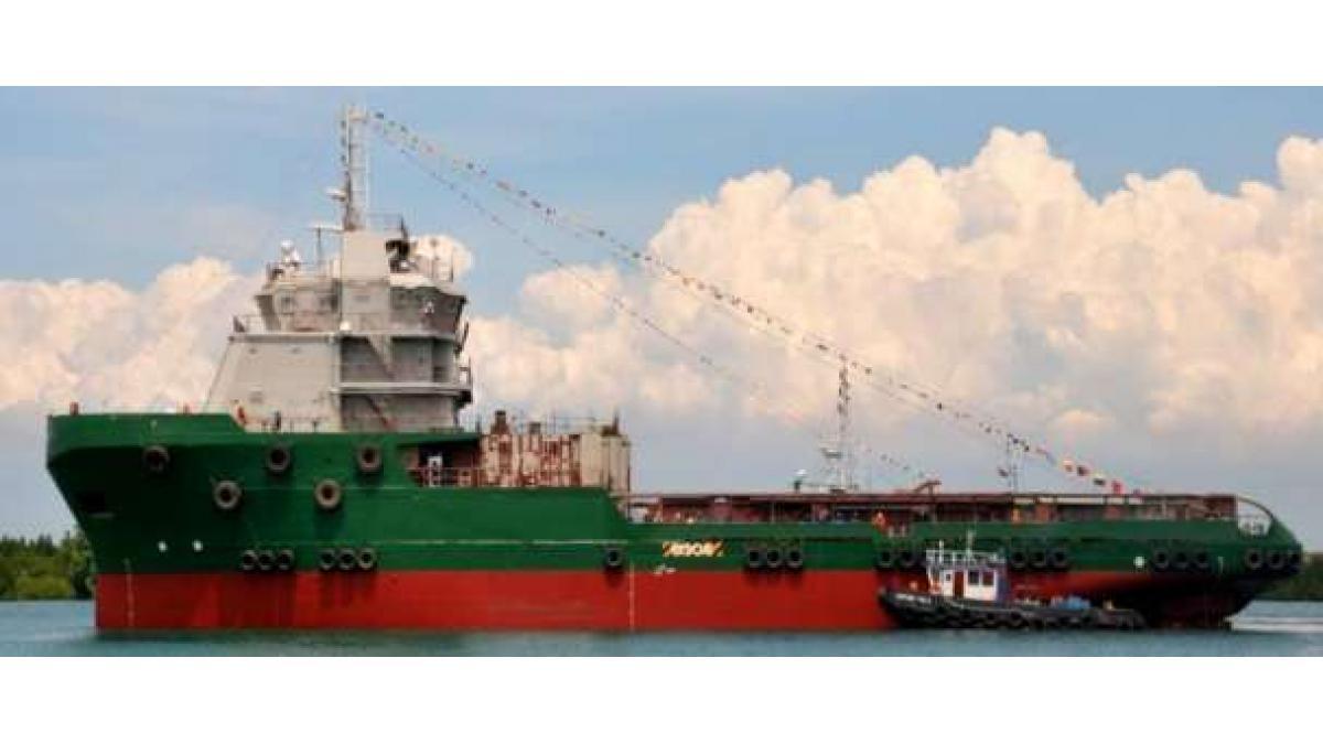A green and red marine vessel with blue sky and clouds