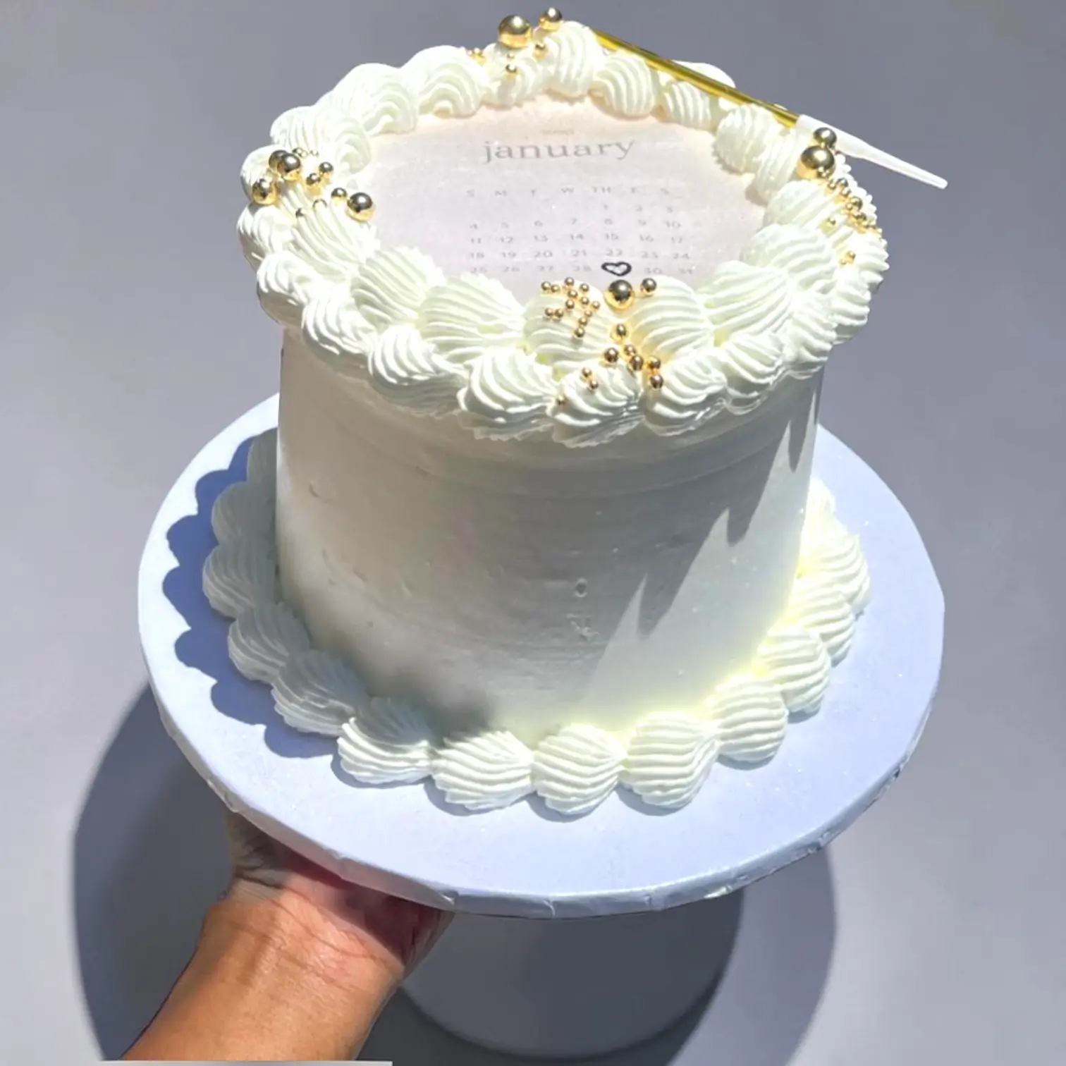 Cream cake with decorative piping and a calendar on top