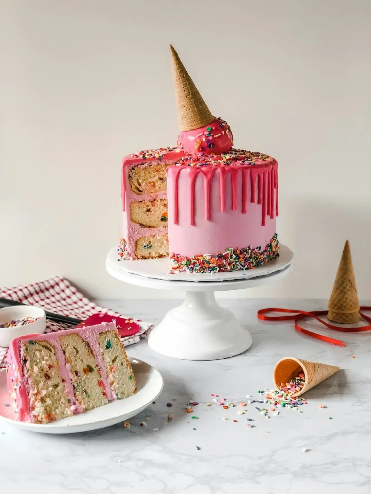 Vibrant pink drip cake with sprinkles and an ice cream cone