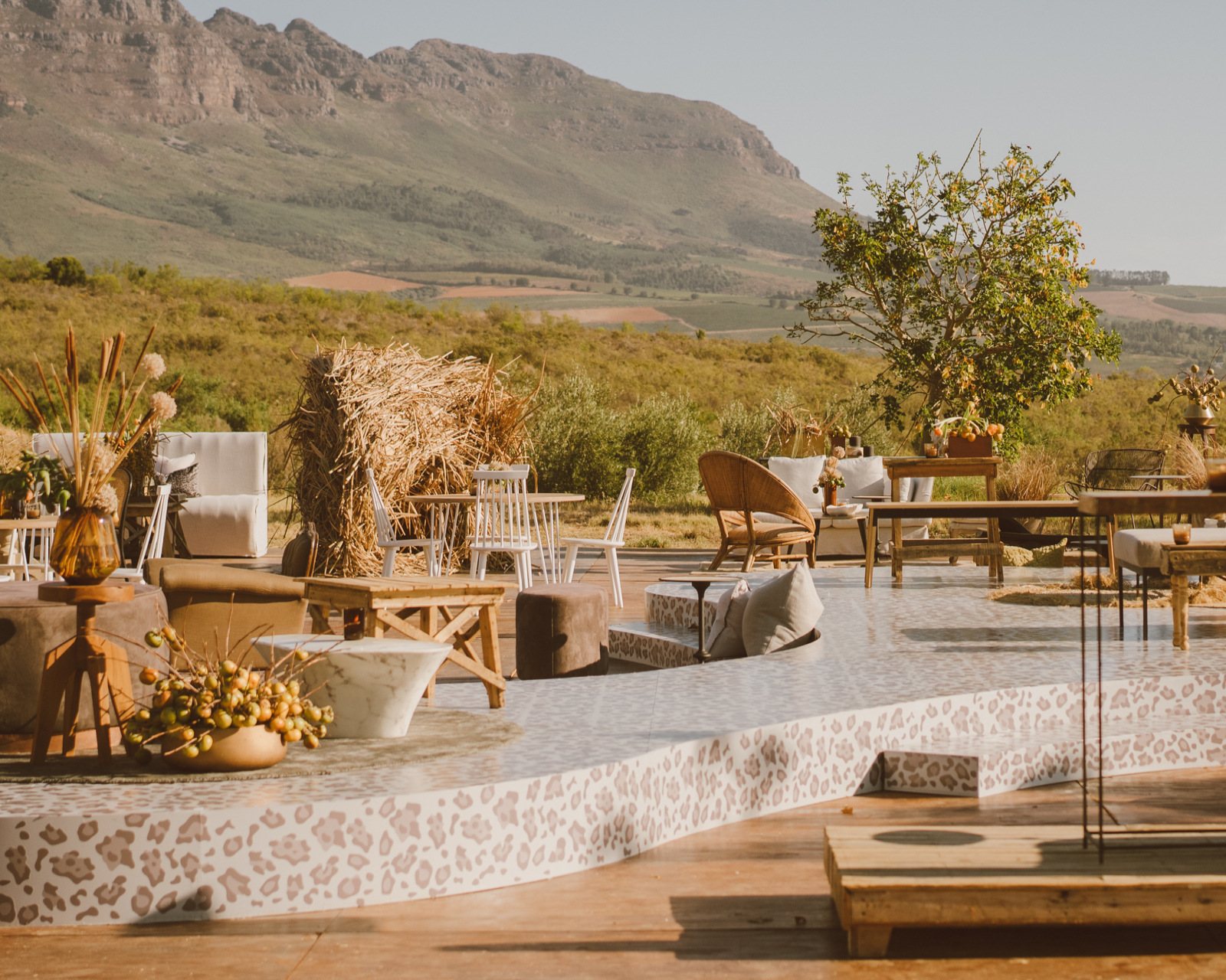 Outdoor event setup with rustic furniture and mountain backdrop