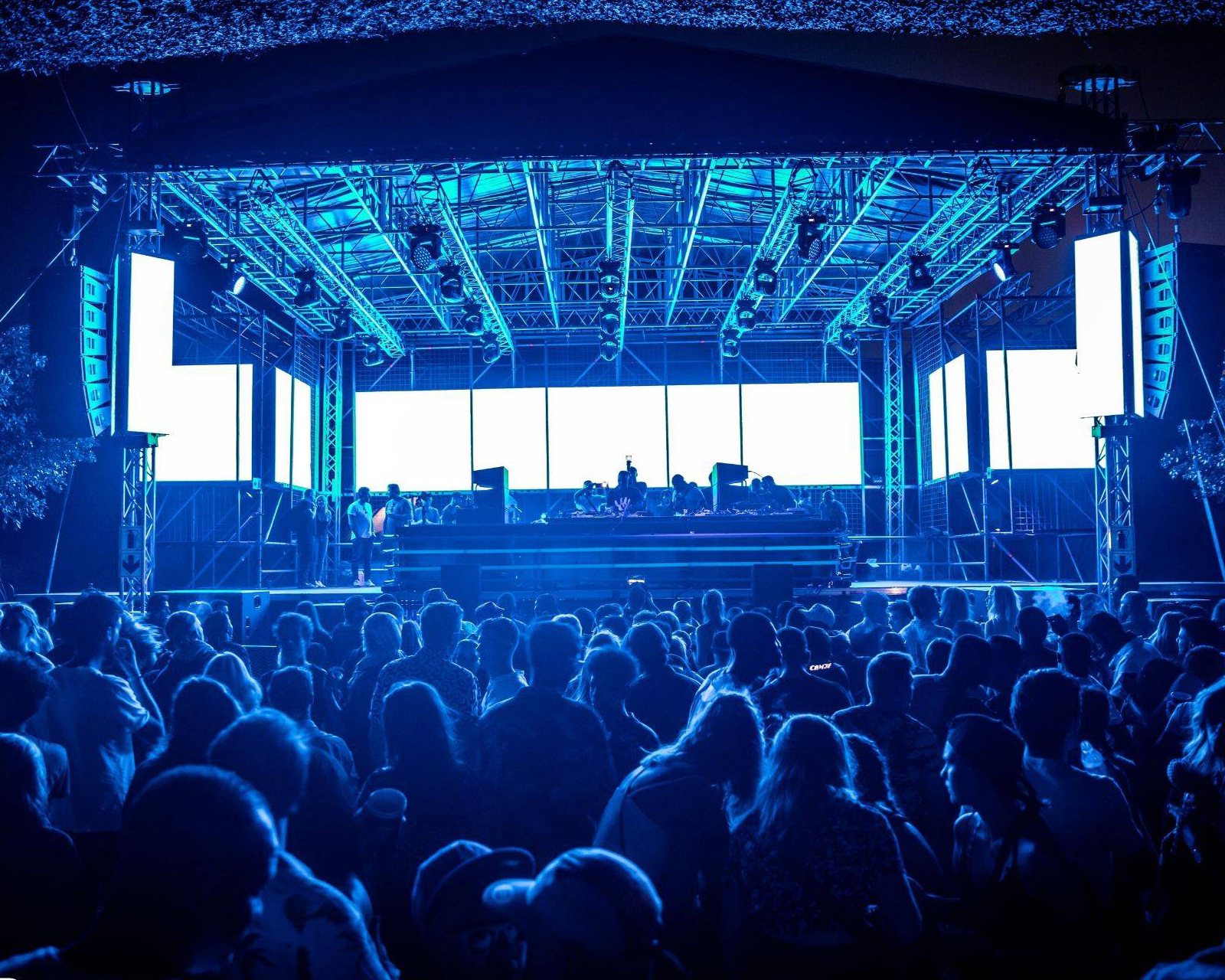 A well-equipped stage with blue lighting before a large crowd