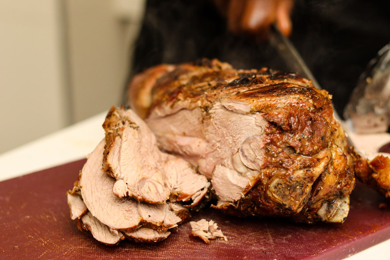 A chef slicing succulent roast meat on a cutting board.
