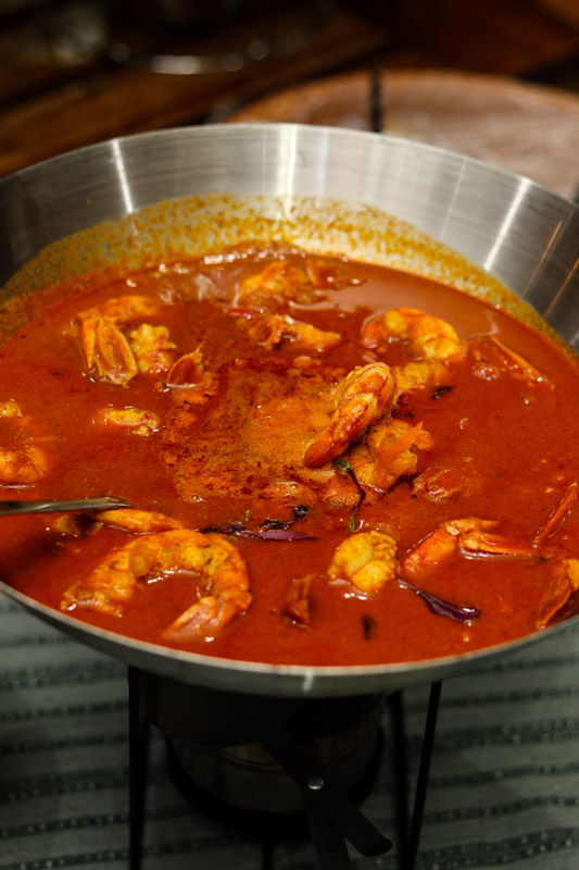 A pot of seafood curry with shrimp and spices