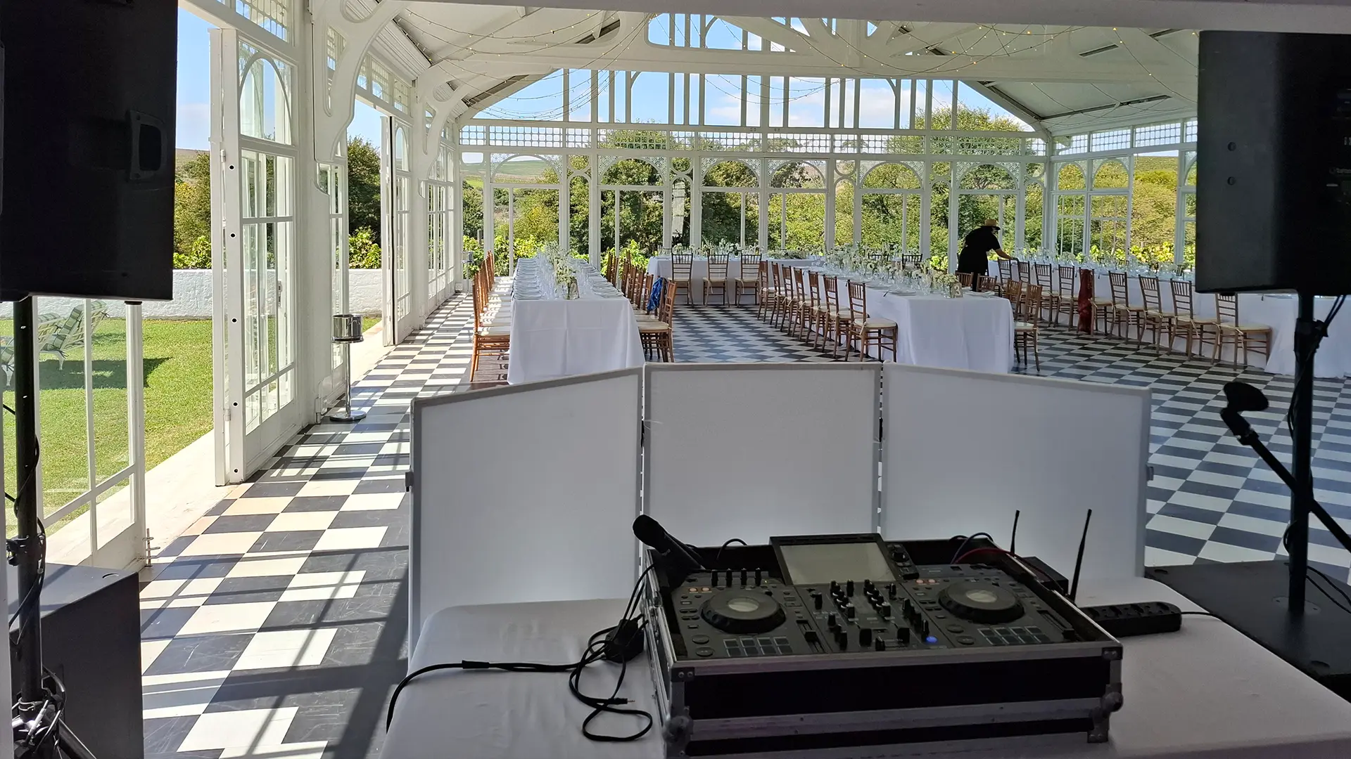 DJ setup in a spacious event venue with tables arranged for guests.