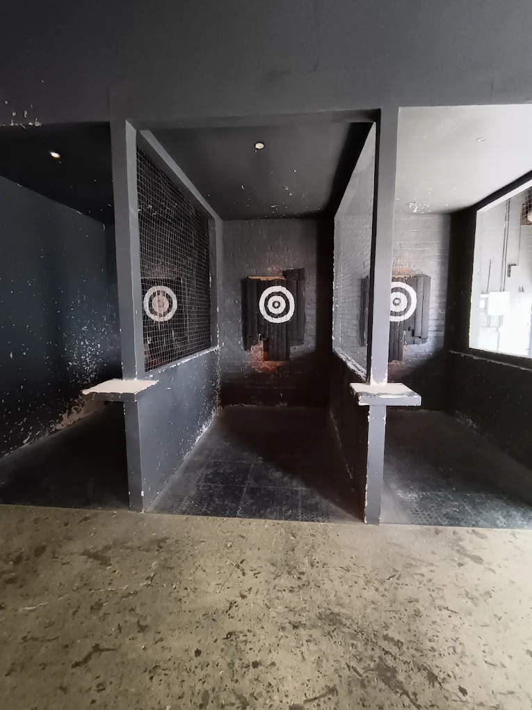 Three axe throwing lanes with targets in a dark room.