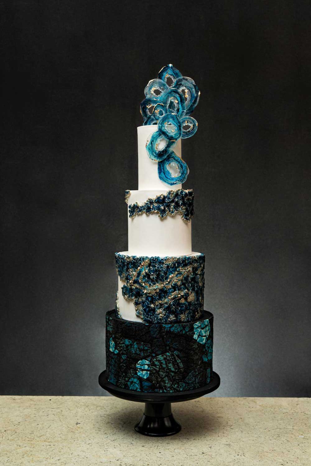 Four-tier wedding cake with blue and black detailing