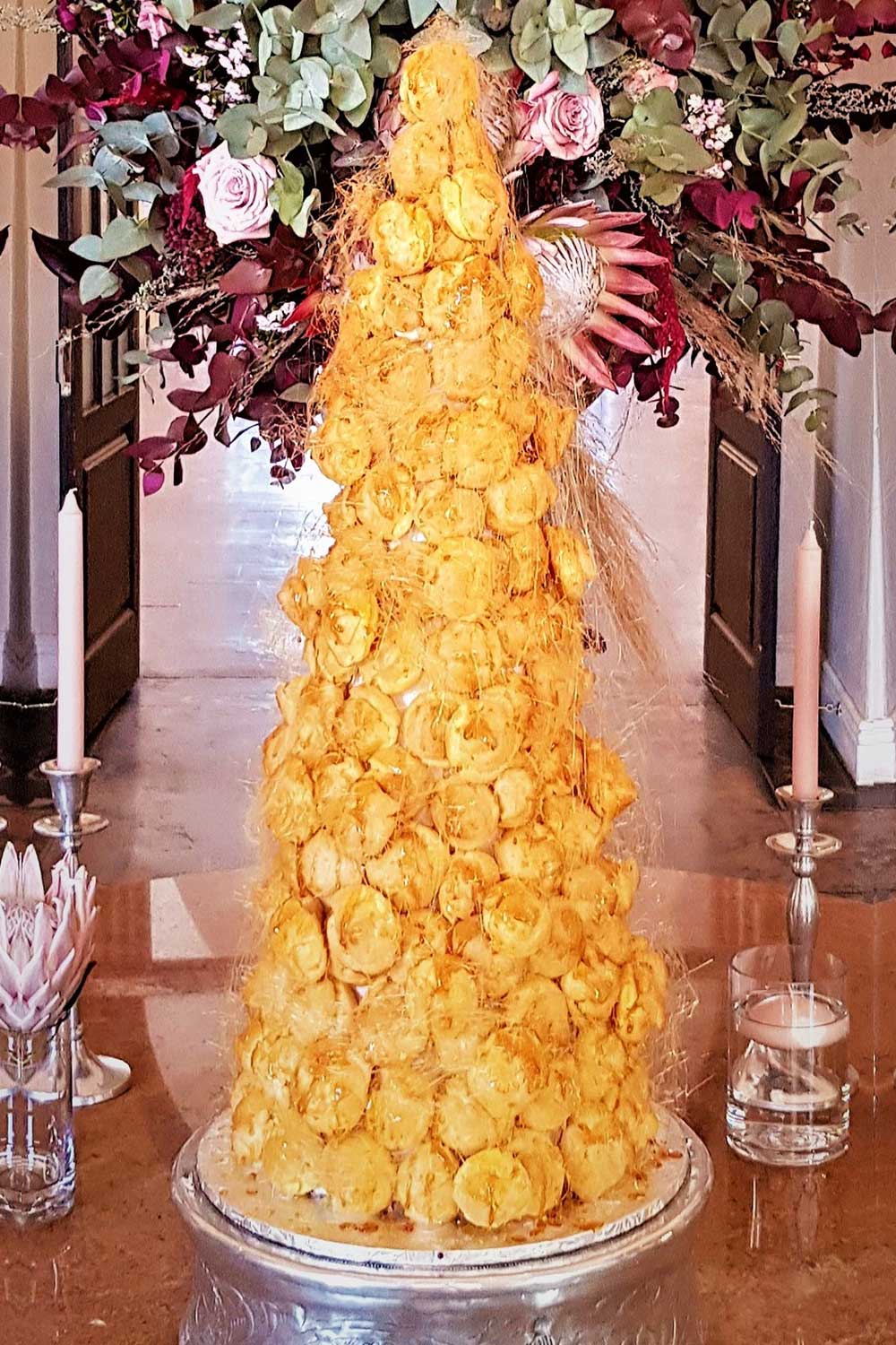 A floral arrangement atop a cake with yellow pastries and delicate flowers.