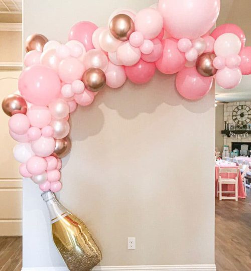 Pink and gold balloon arch with a champagne bottle design.