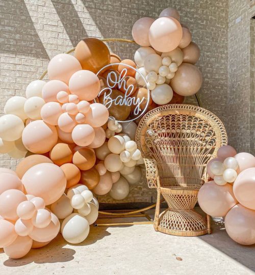Organic balloon backdrop with a rattan chair and signage