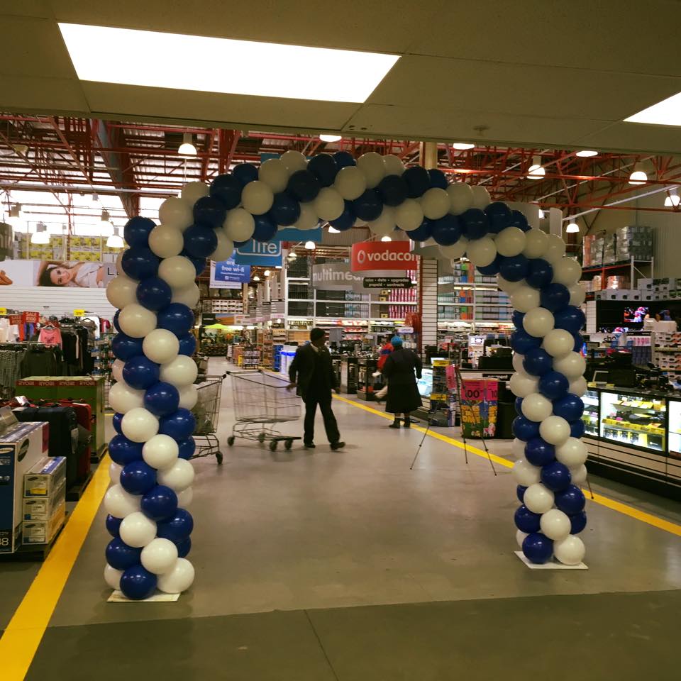 A blue and white balloon arch in a store entrance.