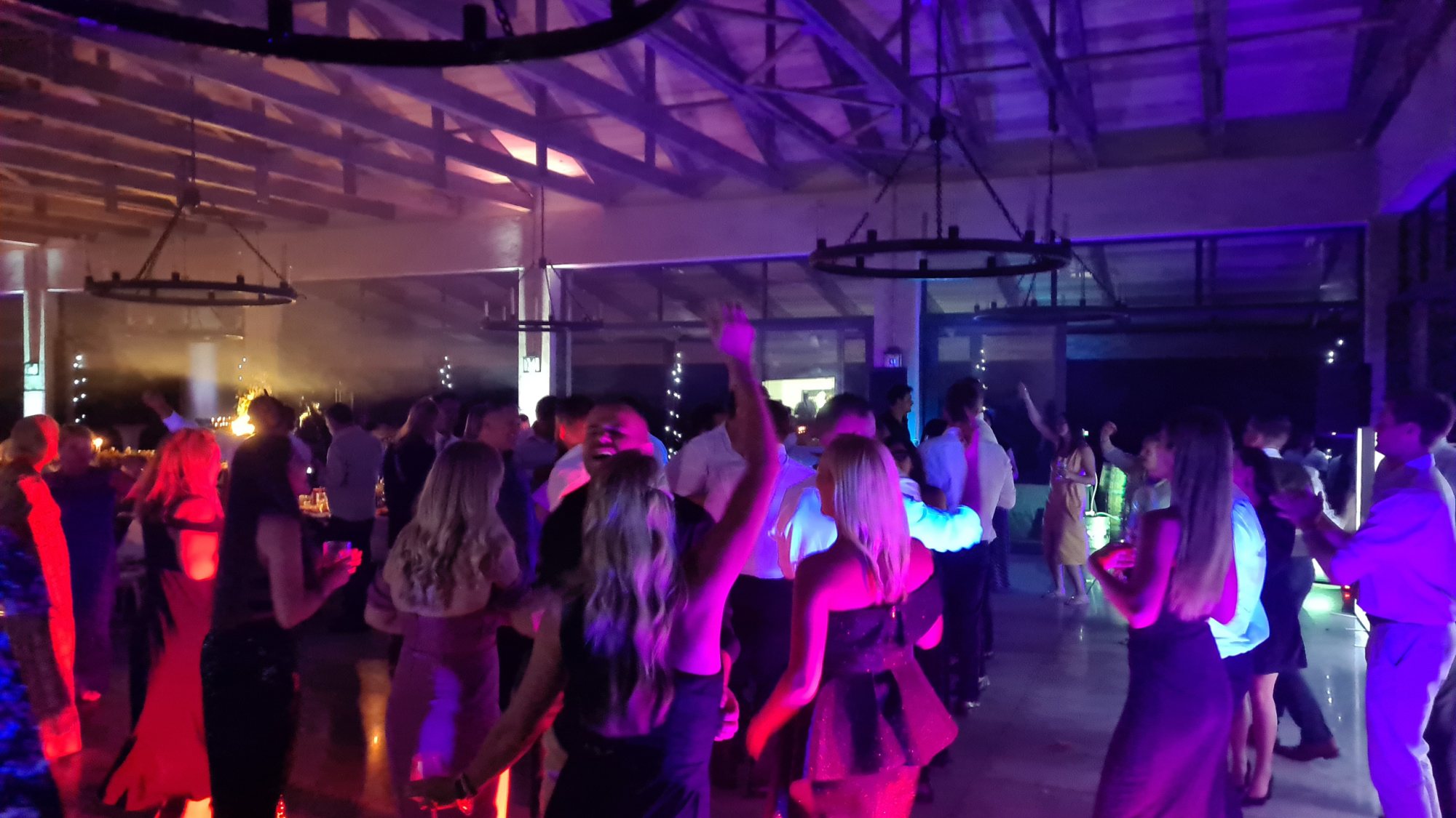 Guests dancing at a vibrant event with colorful lighting.