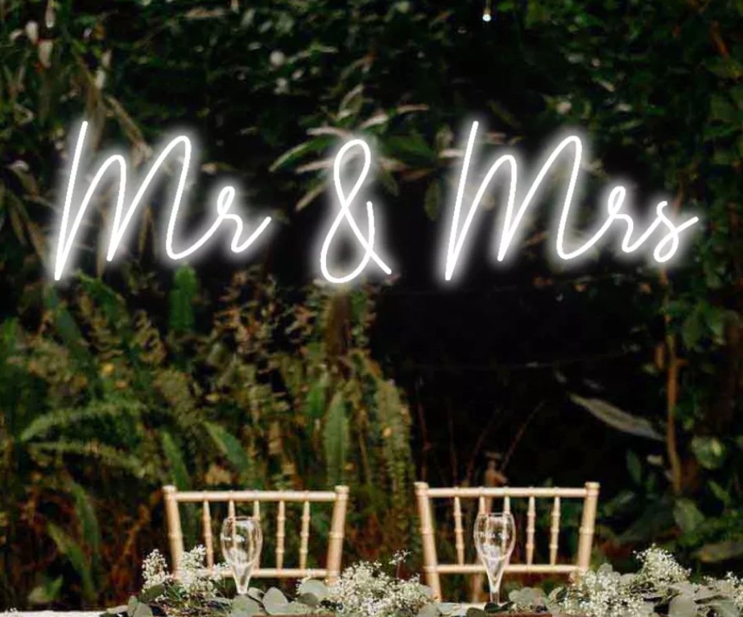 Neon 'Mr & Mrs' sign over chairs with glasses