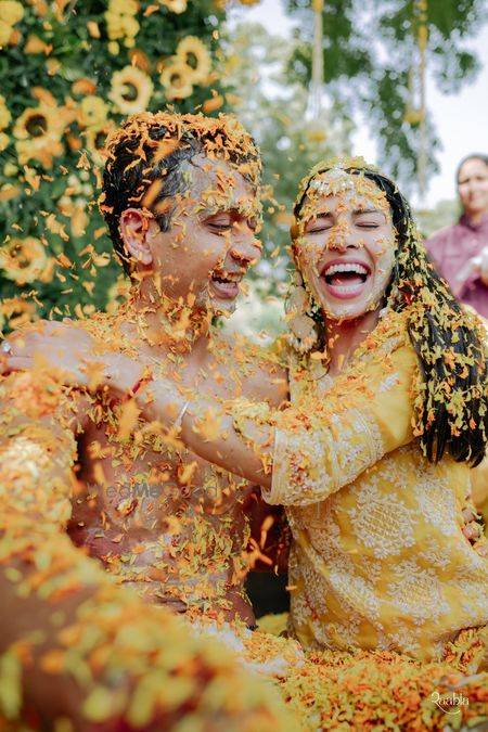 A couple covered in colorful flower petals during a celebration.