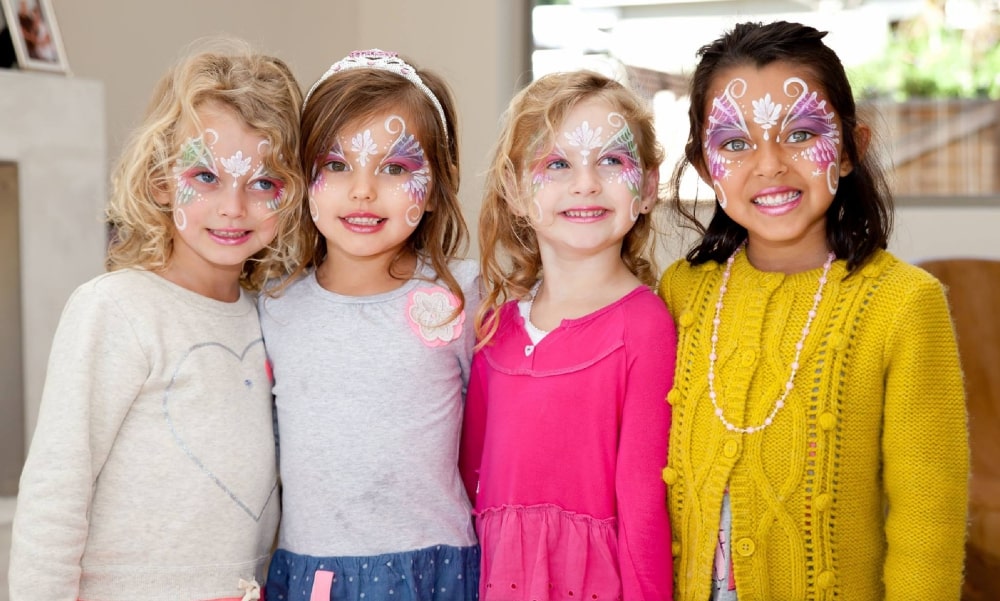 Four girls with colorful face paint smiling
