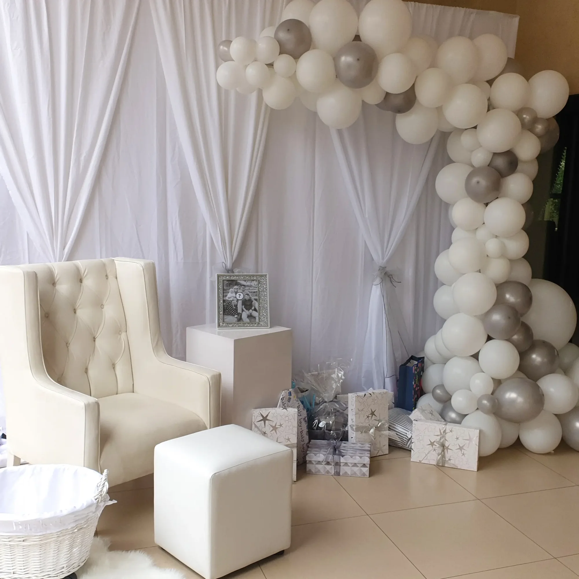 Balloon arch with white and silver balloons and a stylish seating area