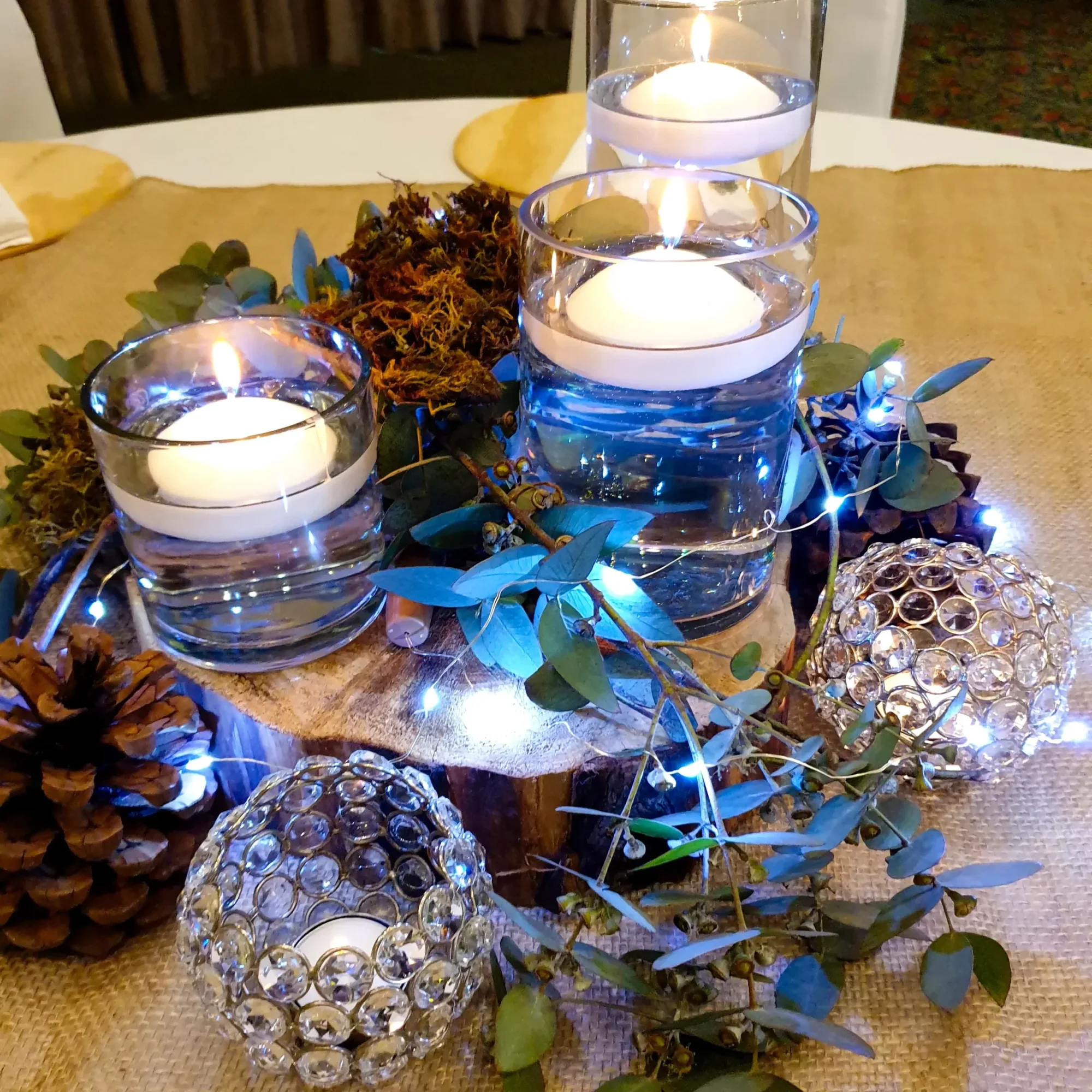 Rustic table centerpiece with candles, greenery, and decorative accents.