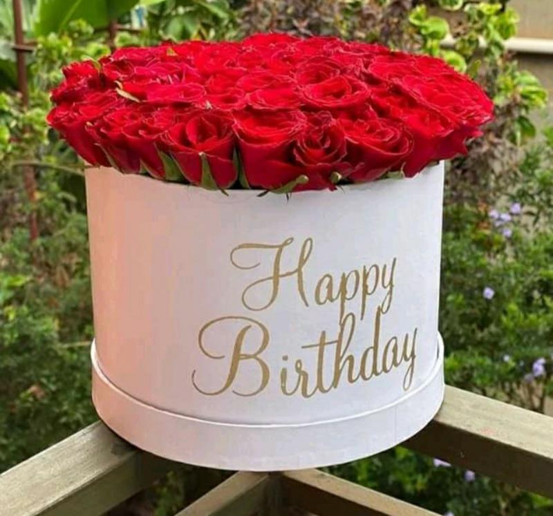 Round box filled with red roses and 'Happy Birthday' text