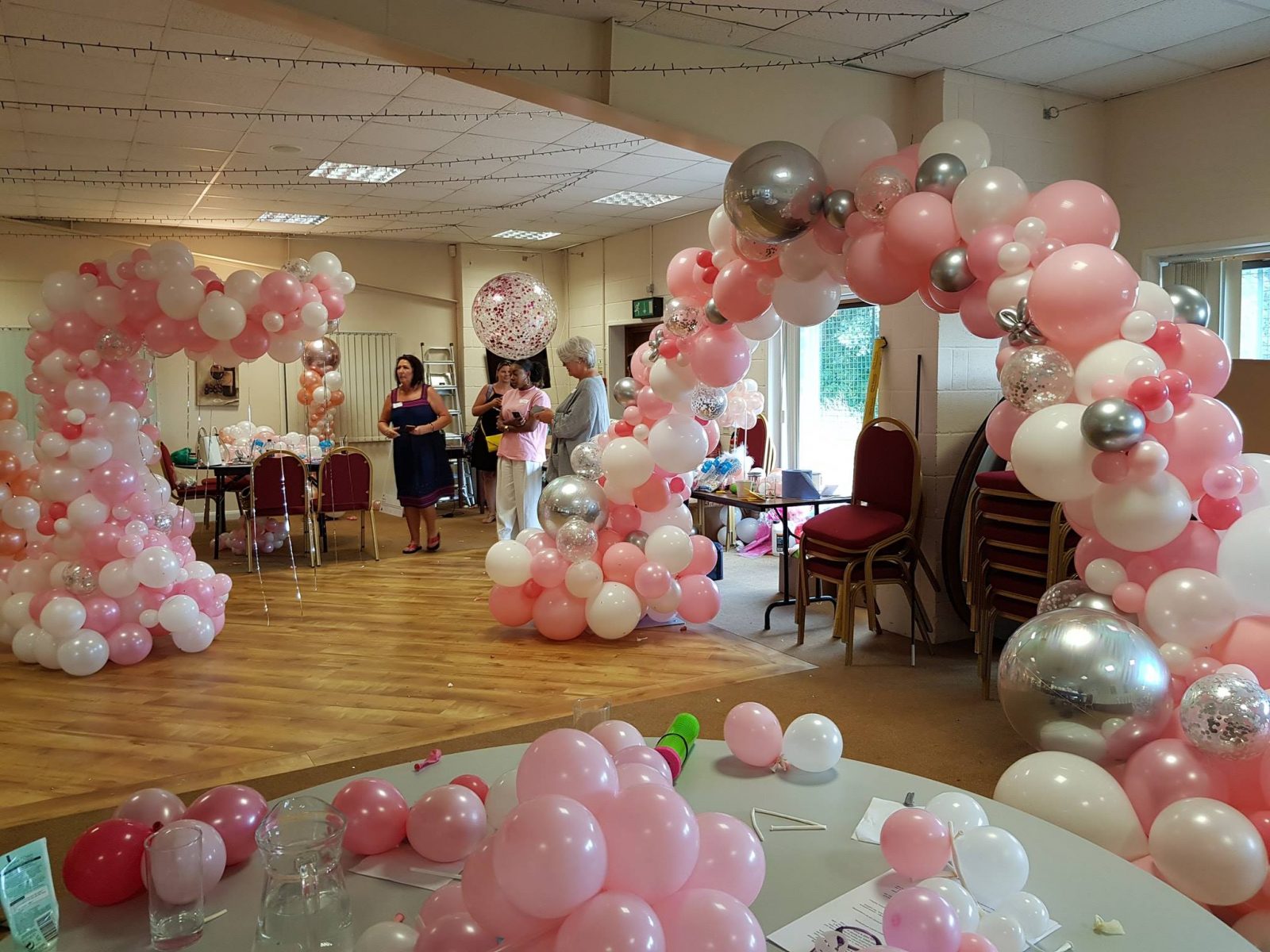 Two pink and white balloon arches in a spacious venue