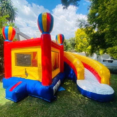 Brightly colored hot air balloon water castle with slide in a garden