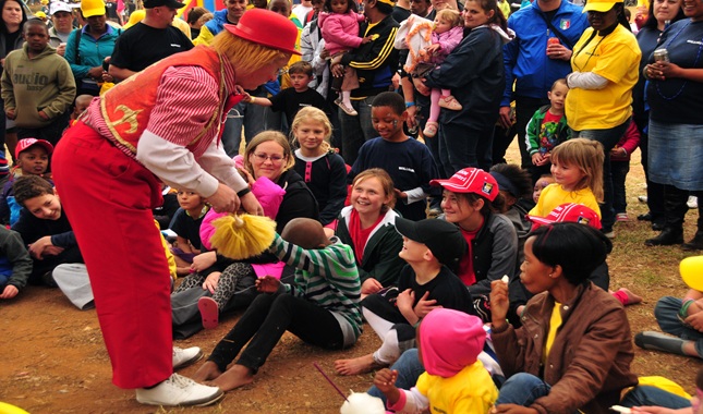 A performer engaging with a group of children at an outdoor event.