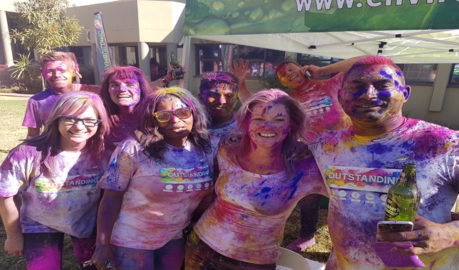 Group of people covered in colorful powder during a celebration.