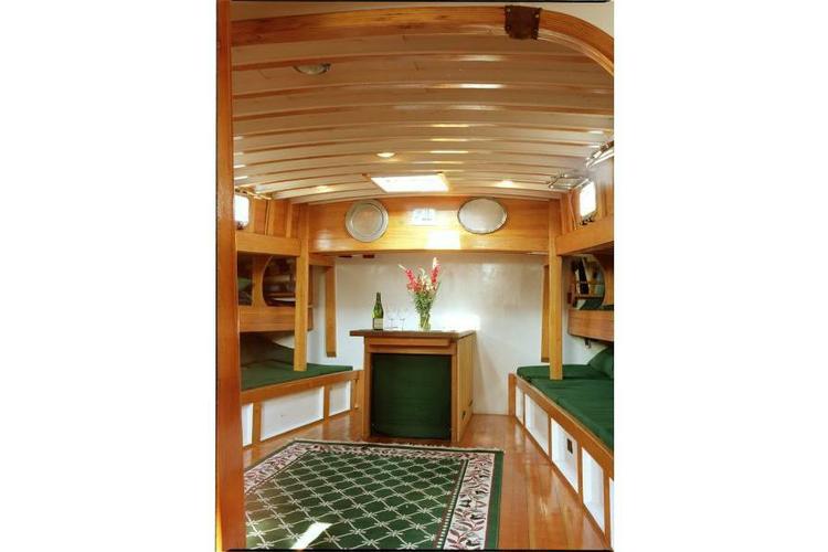 Wooden boat interior with green cushions and a flower vase