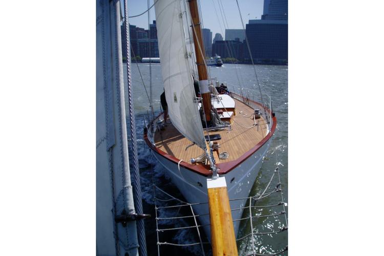 Bow of a sailing yacht with white sails on water