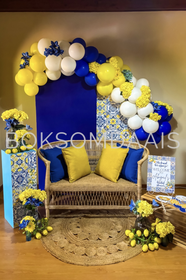 Event styling with blue and yellow balloons, flowers, and seating