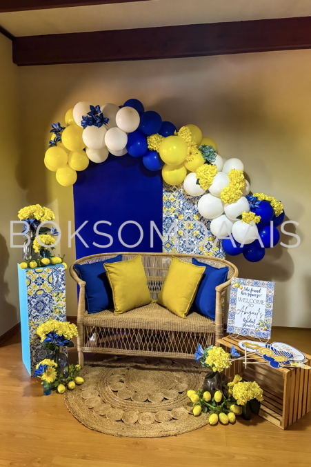 Lounge setup with yellow balloons, blue backdrop, and decorative elements