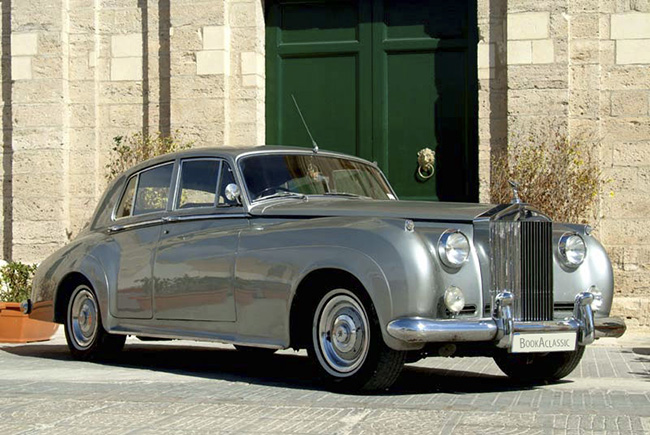 Classic silver Rolls Royce parked in front of a building
